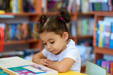 Picture of a female child reading a book in a library