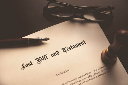 Picture of a last will and testament that has a pen, a pair of glasses, and a seal sitting on top of it