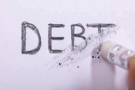 Picture if the word debt written in pencil, being erased with a pencil eraser