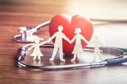 Picture of paper cutouts of a family holding hands in front of a red heart and a stethoscope