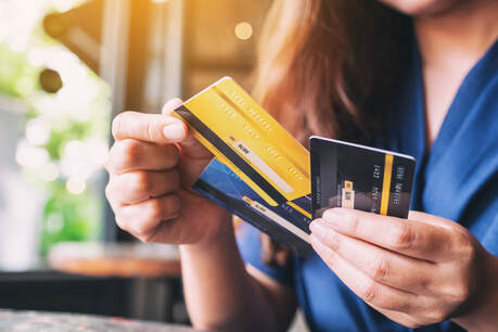 Picture of a female choosing a credit card from a group of 3 credit cards