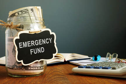 Picture of a jar labeled Emergency Fund full of money on a table with a ledger book, glasses, and a calculator