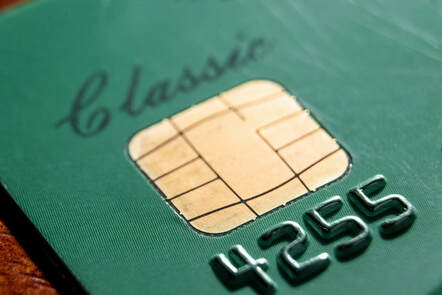 Closeup picture of a green credit card with a gold EMV chip in it