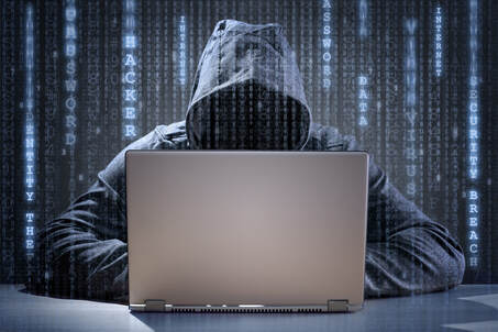 Picture of a hacker wearing a hooded sweatshirt siting in front of a laptop computer